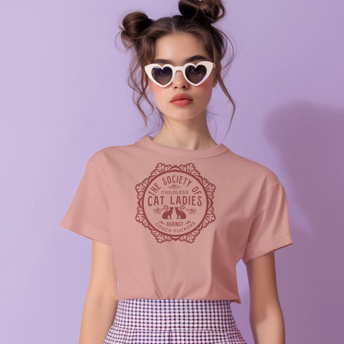 The Society of Childless Cat Ladies Against Couch Fuckers" 2024 election T Shrort design featuring two cats in an ornate circular frame, available in white and purple.